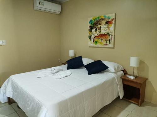 1 dormitorio con 1 cama blanca grande con almohadas azules en HOTEL Apartamentos Herradura #5 Familiar, en Herradura