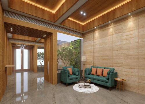 a lobby with two green chairs and a table at Sarovar Portico Morbi in Morbi