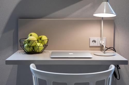 a desk with a laptop and a basket of fruit at Redstone Apartments in Rīga