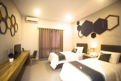a hotel room with two beds and a television at Casananta Seminyak in Seminyak