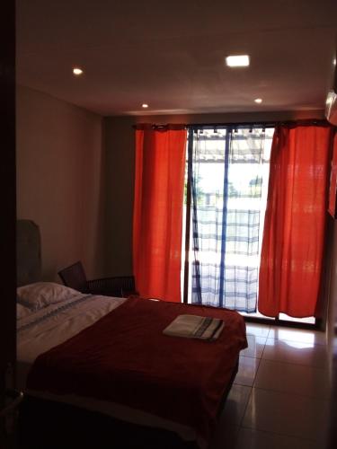 N1 1 Apartamento Completo 2 Dormitorios en Centro de Artigas في أرتيجاس: غرفة نوم بسرير ونافذة ذات ستائر حمراء