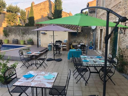 La RedorteにあるLa Marelle chambre d hôtes à 500m du Canal du Midiのテーブルと椅子と傘のあるパティオ