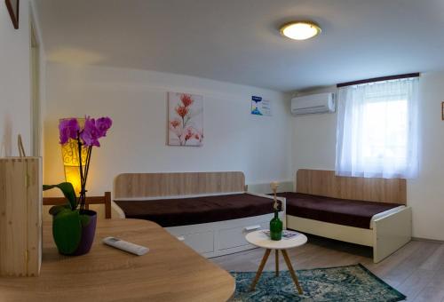 a living room with two beds and a table at Silentium Garden Apartman Sárvár in Sárvár