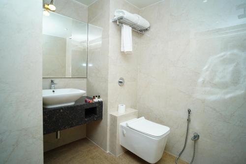 a white bathroom with a sink and a toilet at Orange Tree Hotels in Nagpur