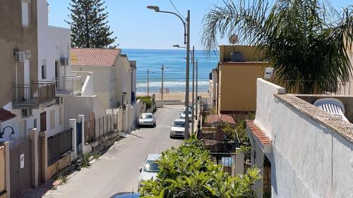 an empty street with cars parked on the beach at B&B Scala dei Turchi Beach in Realmonte