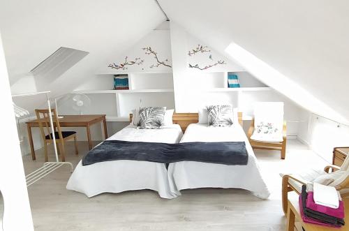 Cette chambre blanche comprend deux lits et un bureau. dans l'établissement IGELDO HOUSE, à Saint-Sébastien