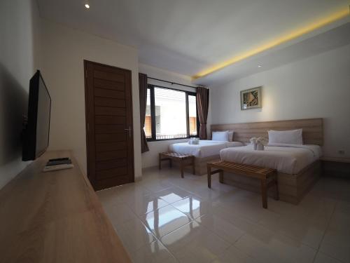a hotel room with two beds and a television at Metta Agara in Kerobokan