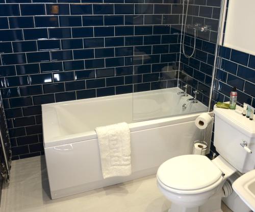 a bathroom with a white tub and a toilet and a sink at The Kings Head Inn in Billingshurst