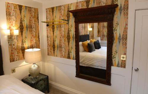 een slaapkamer met een spiegel aan de muur bij The Kings Head Inn in Billingshurst