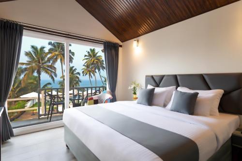 a bedroom with a large bed with a view of the ocean at Stone Wood Beach Resort, Vagator in Vagator