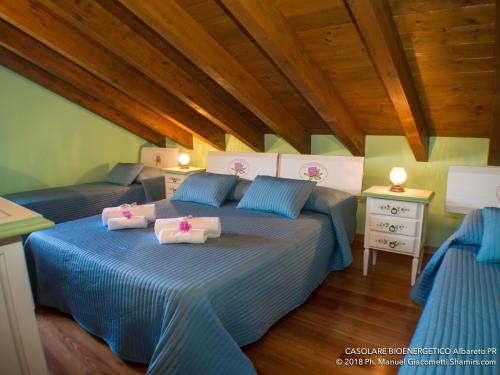 a bedroom with two beds with blue and white sheets at Il Casolare Bioenergetico in Albareto