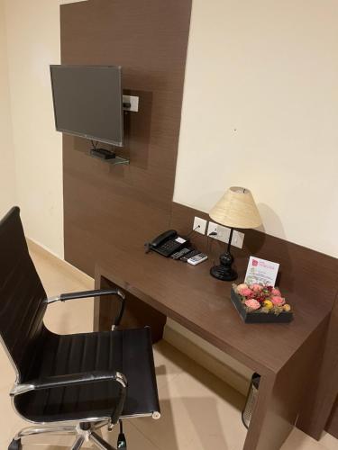 a desk with a phone and a lamp and a desk with a computer at Hotel Yamuna in Adūr