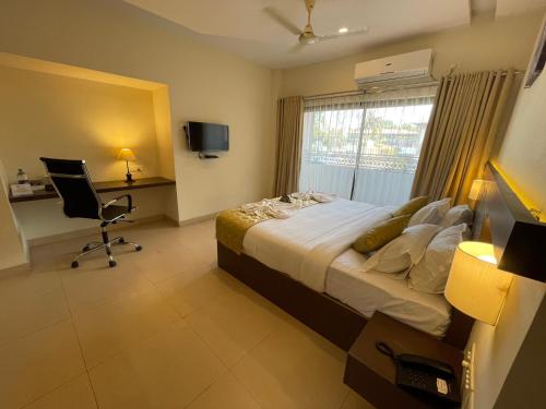 a bedroom with a bed and a desk and a window at Hotel Yamuna in Adūr