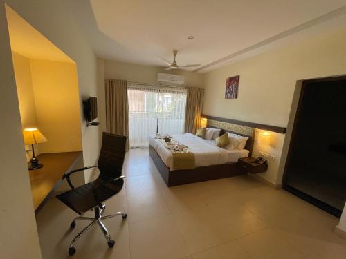 a bedroom with a bed and a tv and a chair at Hotel Yamuna in Adūr