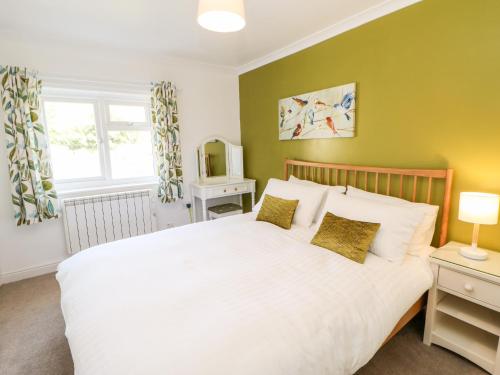 um quarto com uma cama branca e uma televisão em Daisy Cottage em Leyburn