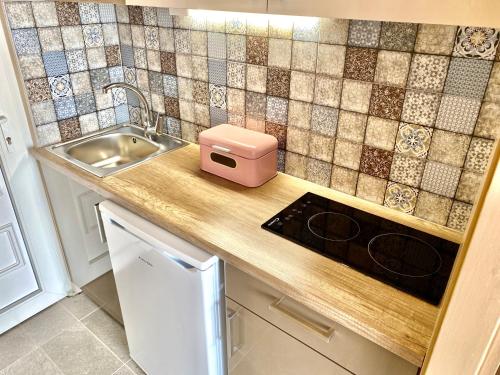 a kitchen counter with a sink and a pink box on it at Aqua Blue Apartmanok - Siófok in Siófok