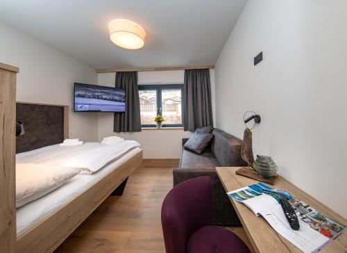 a bedroom with a large bed and a couch at Emma Deluxe Aparthotel ganzjährig beheizter Außenpool in Piesendorf