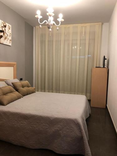 a bedroom with a large bed and a chandelier at Playa Norte 7ºG in Peniscola