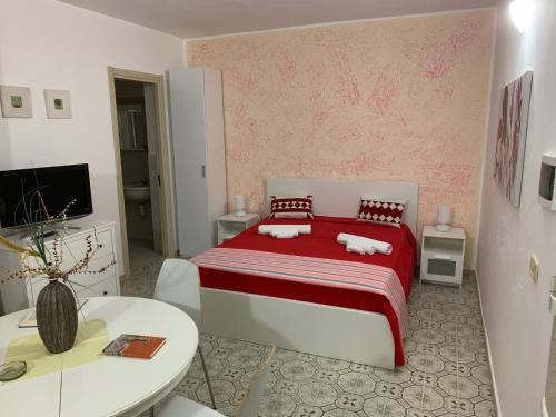 a bedroom with a red and white bed and a table at Eden MONOLOCALE Torre dell Orso in Torre dell'Orso