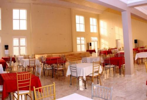 a room filled with tables and chairs with red and white tables at La Diva Hotels - Deluxe in Asaba