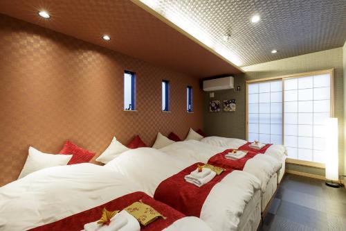 a bedroom with three beds with red and white blankets at ORIGAMI STAY -Futatsubashicho- in Nagoya