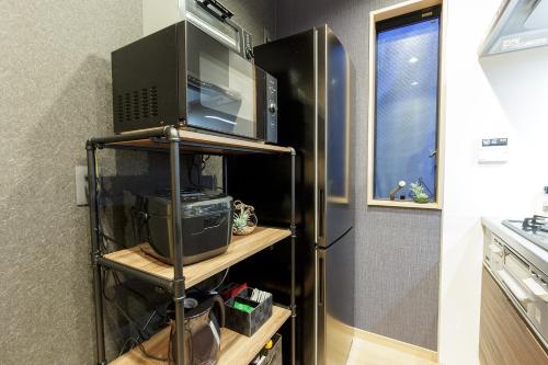 a kitchen with a refrigerator and a microwave at ORIGAMI STAY -Futatsubashicho- in Nagoya