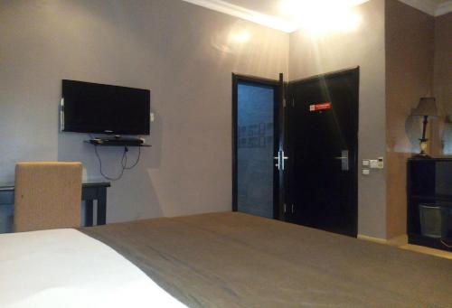 a bedroom with a bed and a tv and a door at Allure Suites - Luxury Room in Surulere