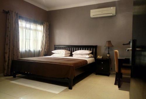 a bedroom with a bed and a window with a air conditioner at Room in Lodge - Allure Suites-surulere in Suru Lere