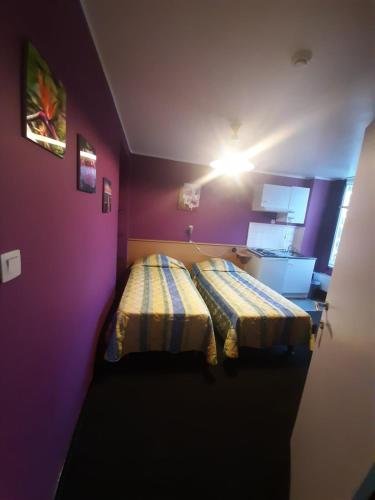 a room with two beds in a purple room at hotel Melissa in Péruwelz