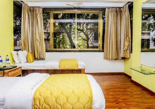 een hotelkamer met 2 bedden en een raam bij Hotel Subhash- Andheri in Mumbai