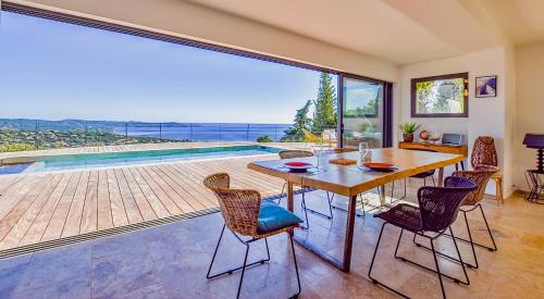 a dining room with a table and chairs and a large window at Découvrez la Villa « The View » in Cavalaire-sur-Mer