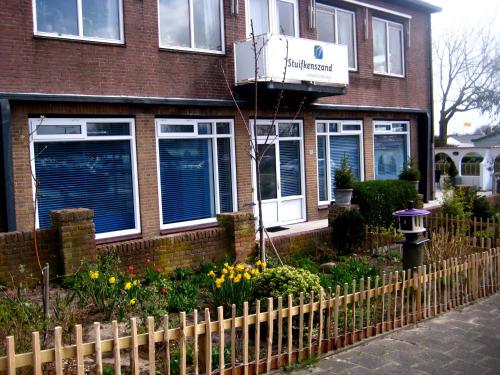 a house with a fence and flowers in front of it at Vakantieappartementen Stuifkenszand in Hoek van Holland