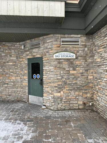 a stone building with a green door and a sign at Highland House 207 Slopeside, Village Area, Ski in out in Snowshoe