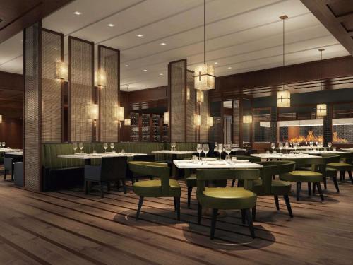 a dining room with tables and green chairs at Fairmont Wuhan in Wuhan