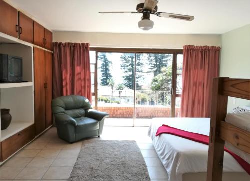 a bedroom with a bed and a chair and a window at Rockview Guest House in Port Edward