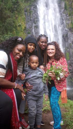 a group of people standing in front of a waterfall at Shimbwe Meadows Home in Moshi