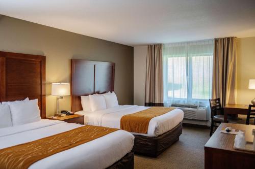 a hotel room with two beds and a desk at Comfort Inn & Suites in Custer