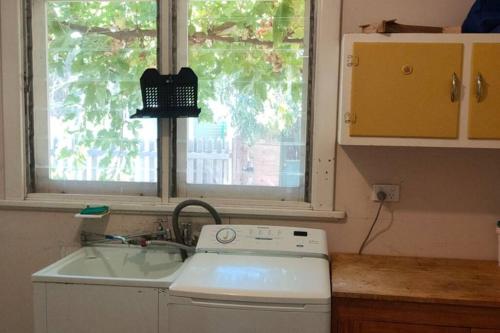 a kitchen with a sink and a stove and a window at The Sunday School Cottage on the Heysen Trail in Burra