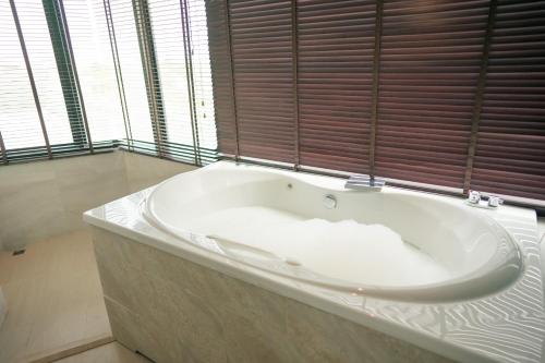 a large white bath tub in a room with windows at Whale Hua Hin - SHA Plus in Hua Hin