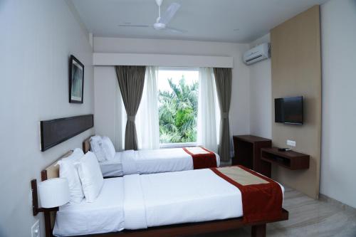 a hotel room with two beds and a window at Hotel Prism - A Boutique Hotel in Jorhāt
