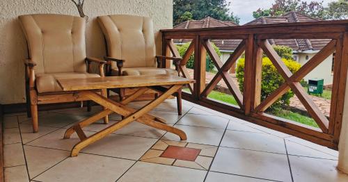 two chairs and a wooden table on a balcony at Jinja Nile Resort in Jinja