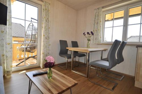 a living room with a table and chairs and windows at Ferienwohnungen Holzidylle in St. Wolfgang