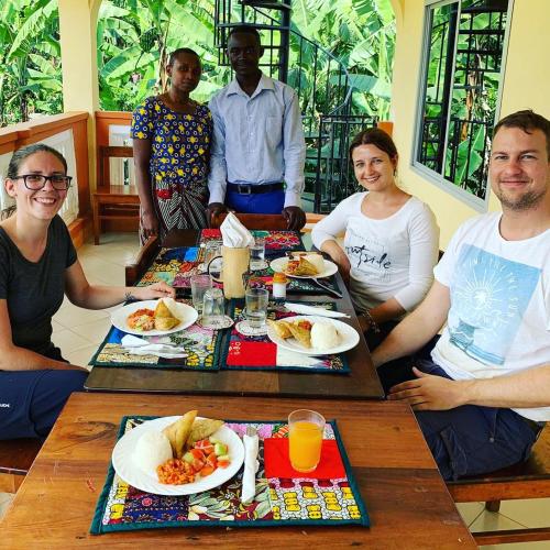 a group of people sitting around a table eating food at Shimbwe Meadows Home in Moshi