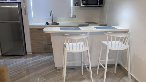 a kitchen with two stools at a kitchen counter at Walk to the Beach 2Min, Cozy, Boutique, Pool, Palmeras Del Mar Isabela in Isabela