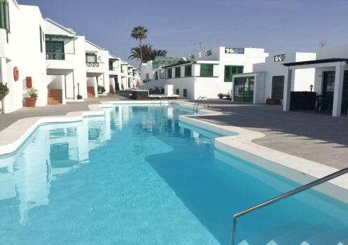 een groot blauw zwembad naast witte gebouwen bij RELAX & POOL NEXT TO THE BEACH APT in Puerto del Carmen