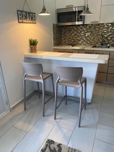 a kitchen with two chairs and a kitchen island at Walk to the Beach 2Min, Cozy, Boutique, Pool, Palmeras Del Mar Isabela in Isabela