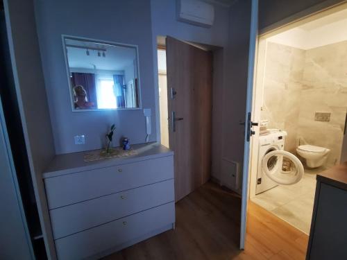 Un baño con lavabo, inodoro y espejo. en Greta, en Świnoujście