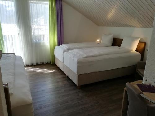 a bedroom with two beds and two windows at Hotel Rhodannenberg AG in Glarus