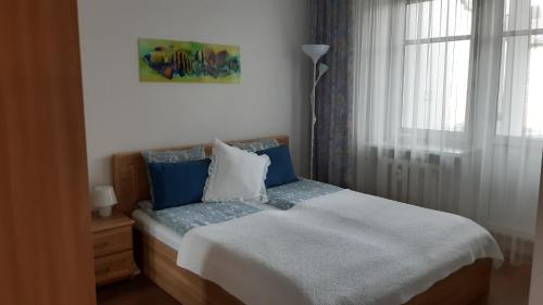 Un dormitorio con una cama con almohadas azules y una ventana en Santariškės Apartment en Vilna