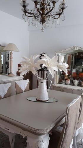 uma mesa branca com flores brancas num vaso em CHAMBRES D'HÔTES CHEZ CATHERINE A REUS chambre bord de mer avec salle de bains privée em Reus